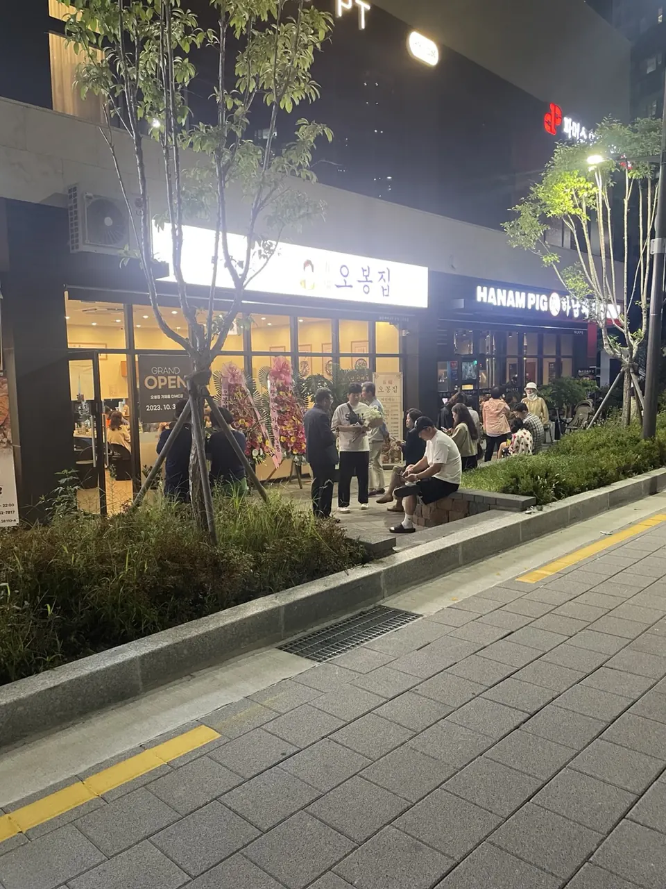 밤에 조명이 켜진 거리 상가에 오봉집 간판이 보이는 매장 외관과 줄 선 손님